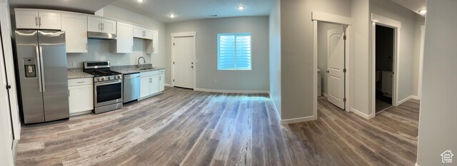 2421 S Blue Water Ln E, Saratoga Springs, UT 84045 - kitchen with baseboards, appliances with stainless steel finishes, light wood-style floors, under cabinet range hood, and white cabinetry