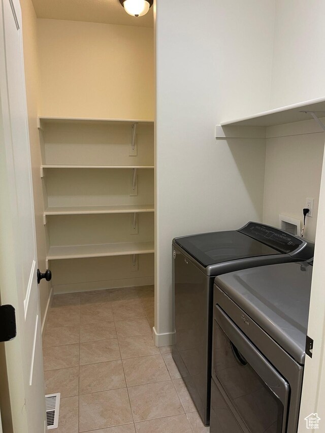 2421 S Blue Water Ln E, Saratoga Springs, UT 84045 - washroom with visible vents, light tile patterned floors, baseboards, laundry area, and washing machine and clothes dryer