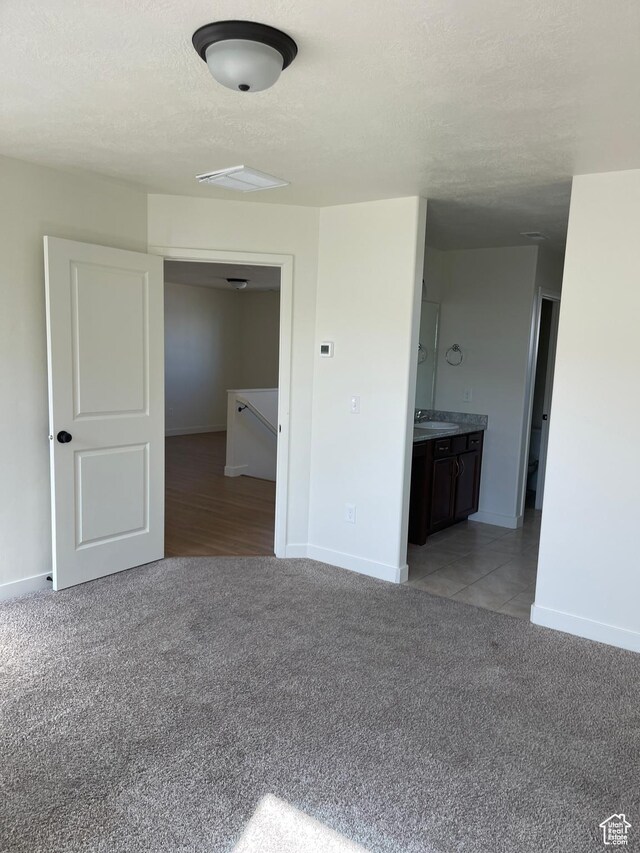 2421 S Blue Water Ln E, Saratoga Springs, UT 84045 - interior space featuring a sink, baseboards, light carpet, and a textured ceiling