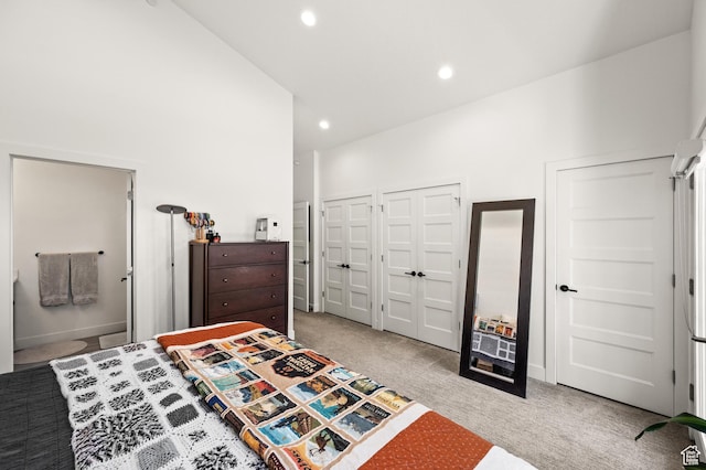 bedroom featuring light carpet, recessed lighting, baseboards, and multiple closets