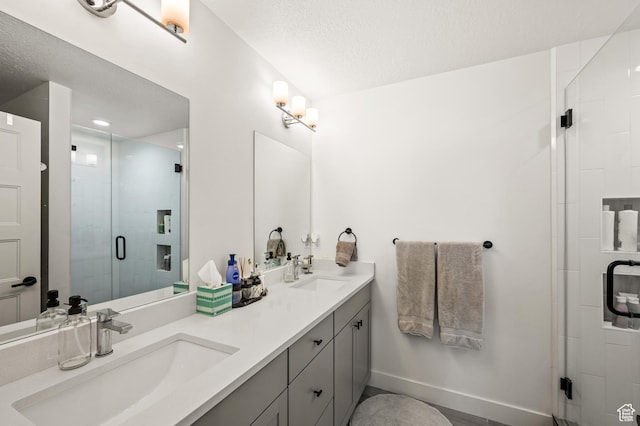 full bath featuring double vanity, baseboards, a stall shower, and a sink