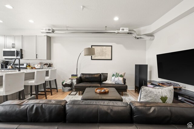 living area with visible vents, recessed lighting, light wood-type flooring, and baseboards