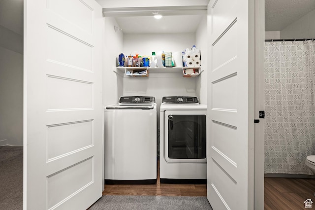 washroom featuring washer and dryer, wood finished floors, and laundry area