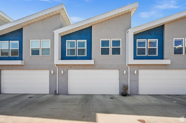 multi unit property with stucco siding and a garage