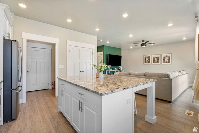 3323 E Gibraltar Ave, Eagle Mountain, UT 84005 - kitchen with white cabinets, light wood finished floors, freestanding refrigerator, and a center island