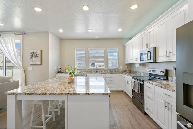 3323 E Gibraltar Ave, Eagle Mountain, UT 84005 - kitchen featuring light wood-style flooring, a sink, stainless steel appliances, white cabinetry, and a center island