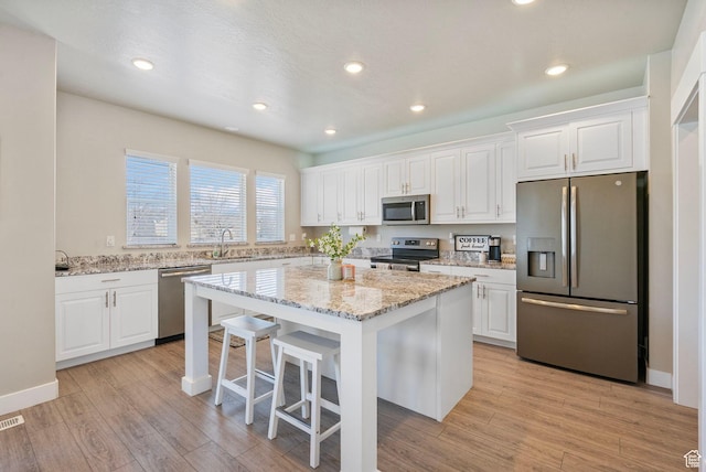 3323 E Gibraltar Ave, Eagle Mountain, UT 84005 - kitchen with a sink, a kitchen island, white cabinetry, and stainless steel appliances