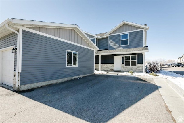 view of front of property with stone siding, driveway, and a garage