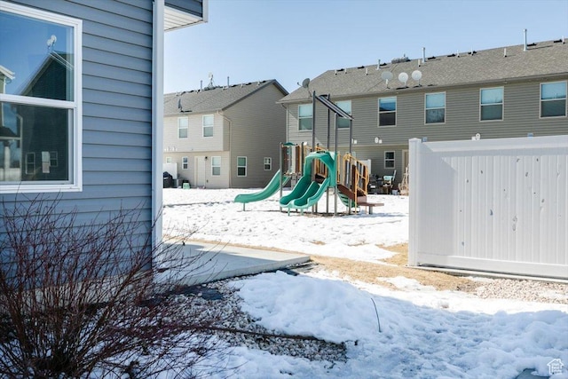 snow covered playground featuring a playground and a residential view