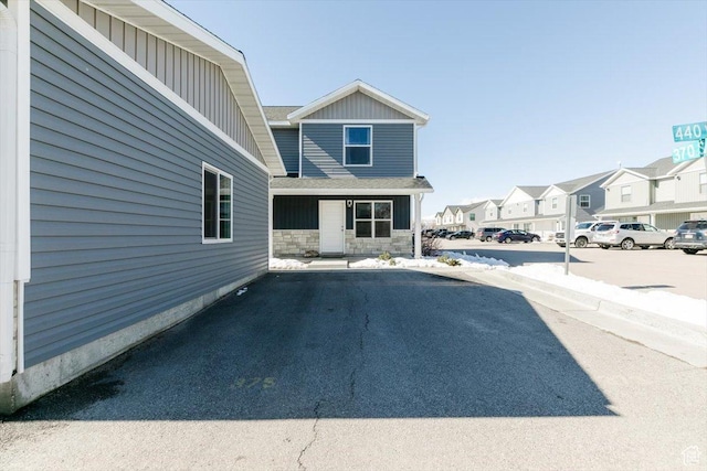 exterior space with stone siding, a residential view, uncovered parking, and board and batten siding