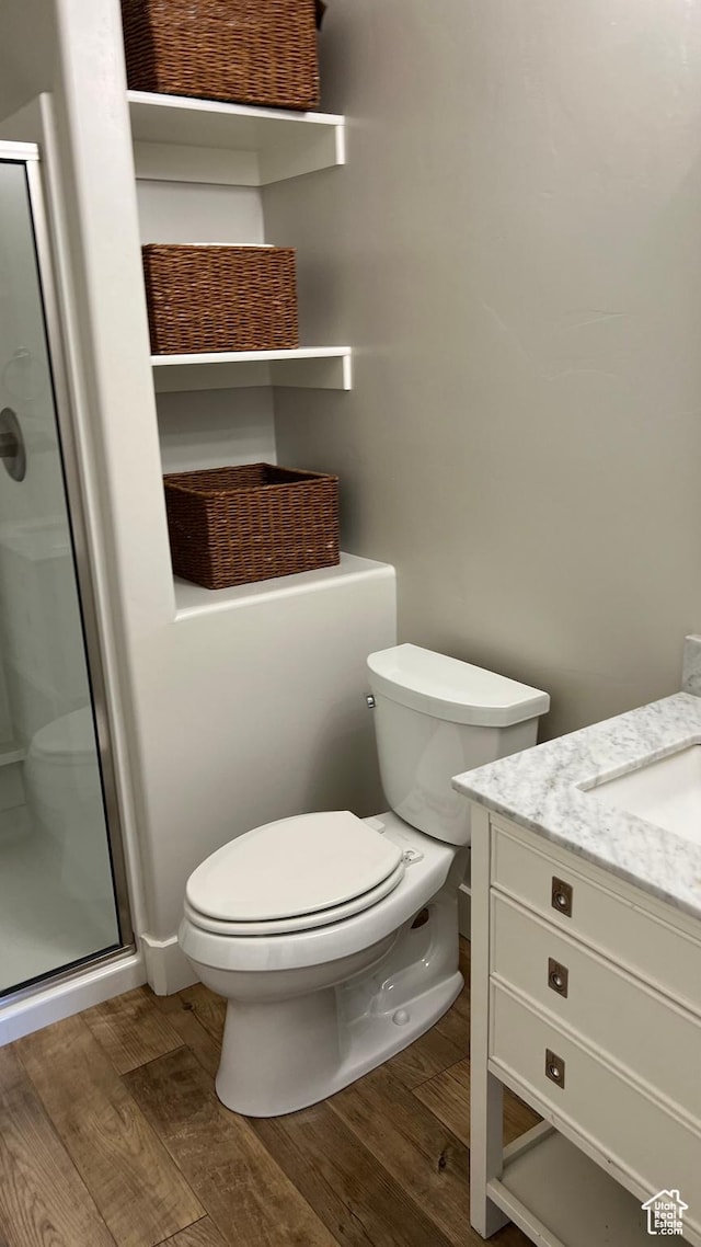 full bath featuring a stall shower, toilet, and wood finished floors
