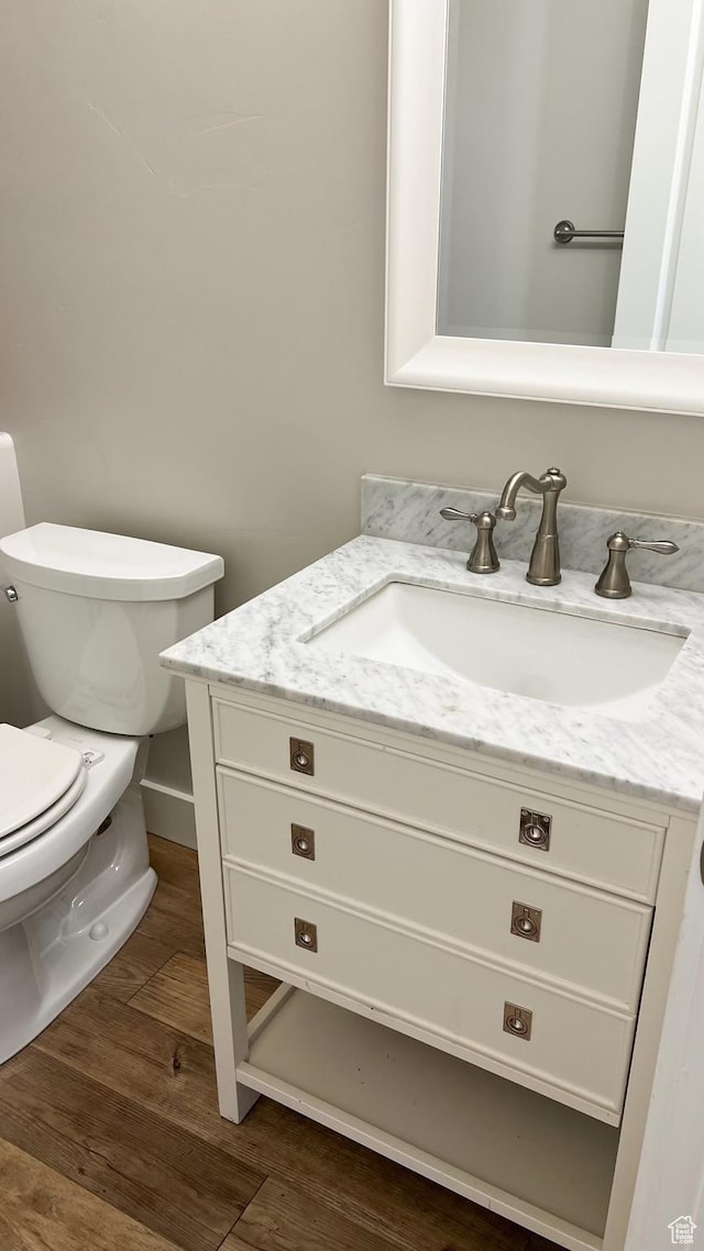half bath with vanity, toilet, and wood finished floors