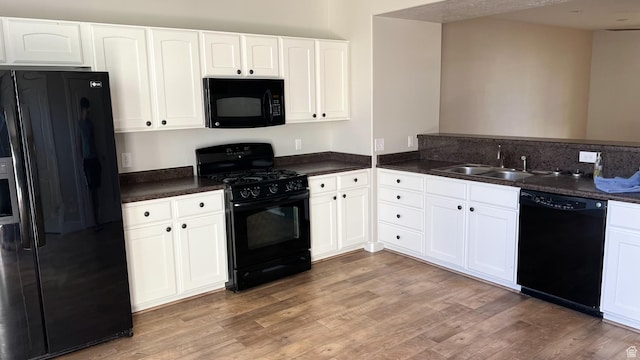 kitchen featuring a sink, dark countertops, black appliances, and light wood finished floors