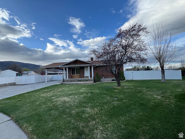 view of front facade featuring an attached carport, a front lawn, concrete driveway, and fence