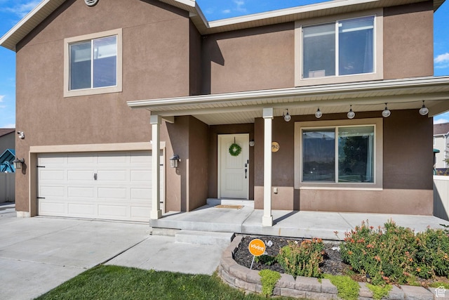 5943 N Bleeker, Stansbury Park, UT 84074 - view of front of house with covered porch, a garage, stucco siding, and driveway