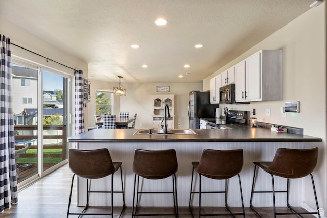 5943 N Bleeker, Stansbury Park, UT 84074 - kitchen with stove, freestanding refrigerator, dark countertops, a peninsula, and recessed lighting