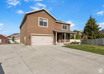 5943 N Bleeker, Stansbury Park, UT 84074 - traditional-style home with a garage, driveway, covered porch, and stucco siding