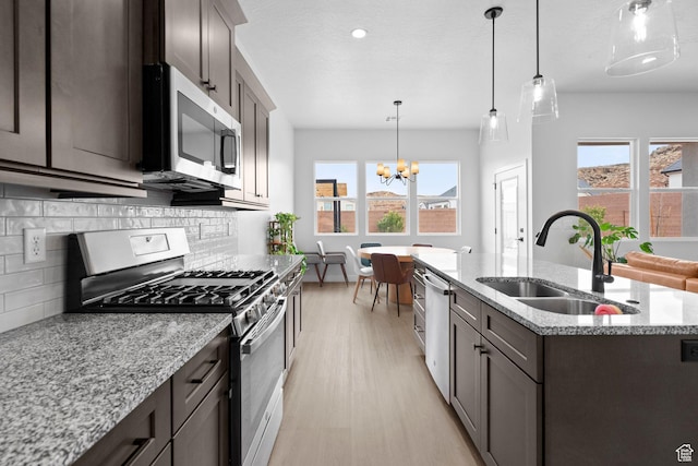 6059 S Bunda Way, St George, UT 84790 - kitchen featuring a center island with sink, a sink, light wood-style floors, appliances with stainless steel finishes, and tasteful backsplash