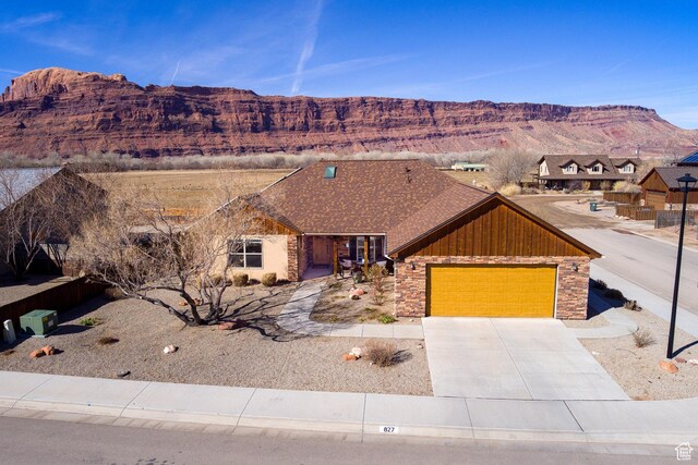 827 N Palisade Dr, Moab, UT 84532 - view of front facade featuring a shingled roof, concrete driveway, a garage, stone siding, and a mountain view