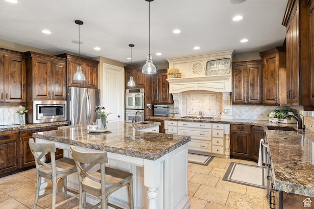 1865 S 3350 E, Heber City, UT 84032 - kitchen featuring appliances with stainless steel finishes, stone tile floors, recessed lighting, backsplash, and a kitchen island with sink