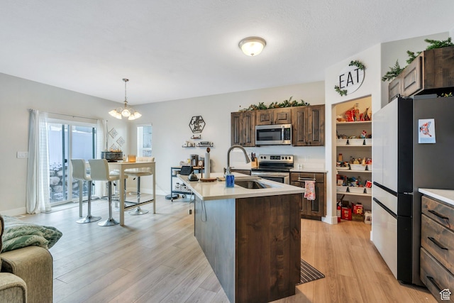 1186 N Buckboard Ln, Spanish Fork, UT 84660 - kitchen featuring appliances with stainless steel finishes, light countertops, a sink, light wood finished floors, and a notable chandelier