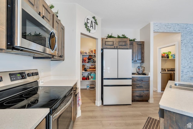 1186 N Buckboard Ln, Spanish Fork, UT 84660 - kitchen with light stone countertops, dark brown cabinetry, appliances with stainless steel finishes, light wood finished floors, and washing machine and dryer