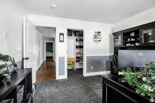 interior space featuring baseboards and dark colored carpet