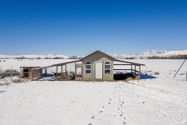 snow covered property featuring an outbuilding, a carport, and a mountain view
