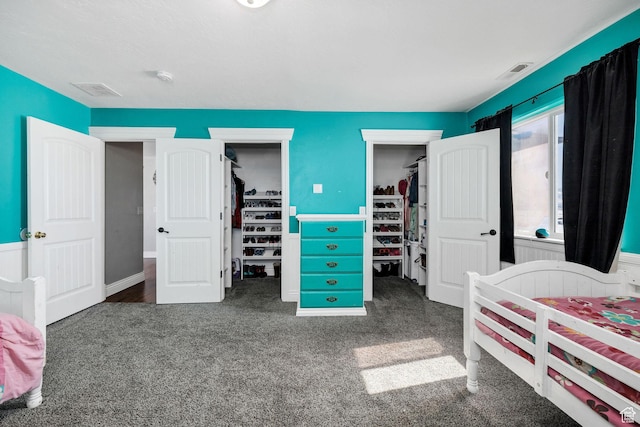 carpeted bedroom with a spacious closet, visible vents, and a closet