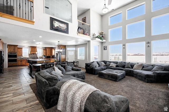 living area featuring a chandelier, a towering ceiling, and wood finished floors