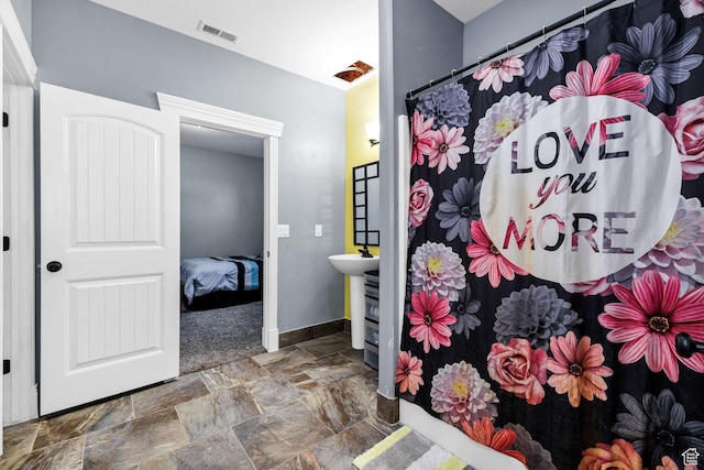 interior space with curtained shower, baseboards, visible vents, and stone finish flooring