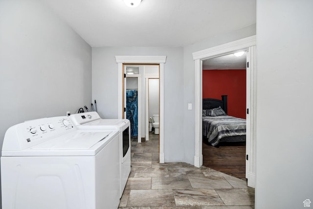 laundry room with laundry area, independent washer and dryer, and stone finish flooring