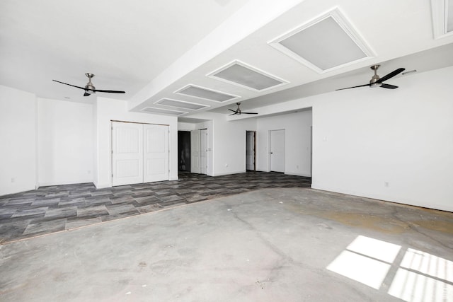 spare room with attic access, unfinished concrete flooring, and ceiling fan
