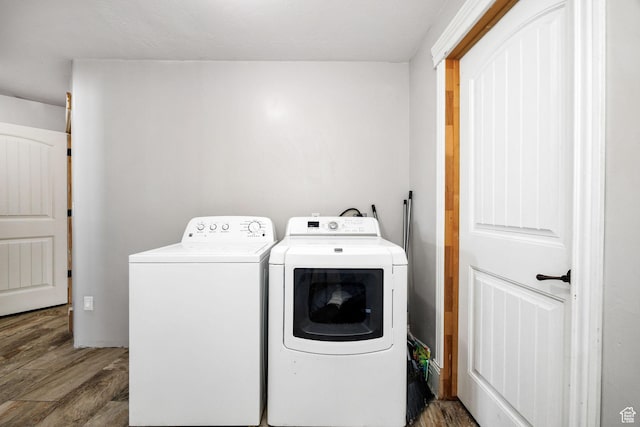 clothes washing area featuring wood finished floors, laundry area, and washing machine and clothes dryer