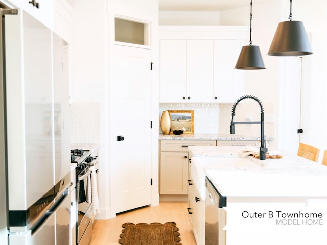kitchen featuring stainless steel range with gas stovetop, a center island with sink, dishwashing machine, light wood-style flooring, and decorative backsplash