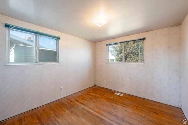 unfurnished room featuring visible vents and hardwood / wood-style flooring
