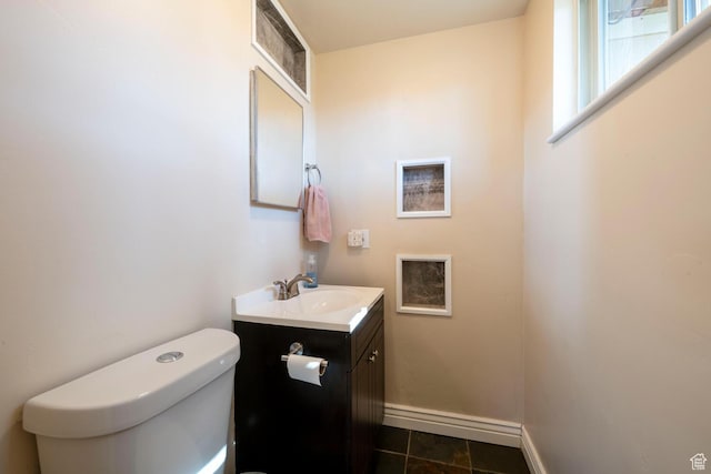 half bath with tile patterned floors, toilet, vanity, and baseboards
