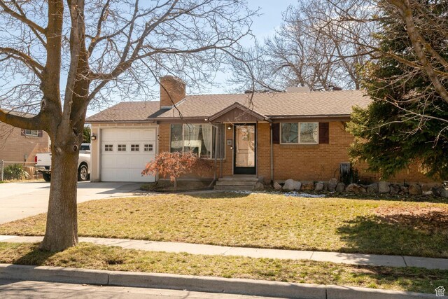 ranch-style house with driveway, an attached garage, a chimney, a front lawn, and brick siding