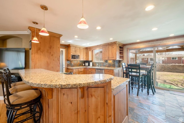 kitchen featuring a breakfast bar, stainless steel appliances, crown molding, decorative backsplash, and light stone countertops