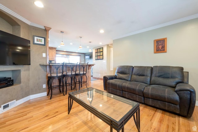 living room with crown molding, baseboards, visible vents, and light wood-type flooring
