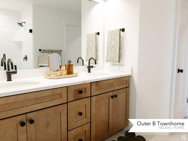 bathroom with double vanity, tiled shower, and a sink