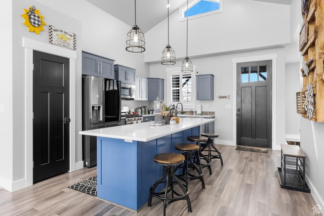3278 S Serviceberry Dr Unit 18, Garden City, UT 84028 - kitchen with stainless steel appliances, a kitchen bar, light countertops, light wood finished floors, and high vaulted ceiling