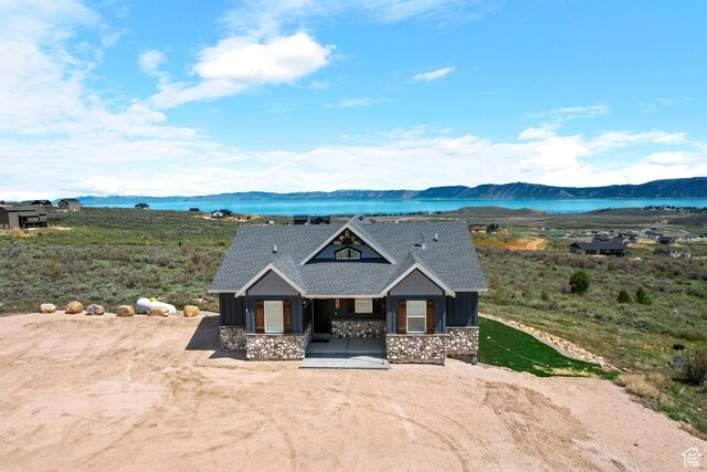 3278 S Serviceberry Dr Unit 18, Garden City, UT 84028 - view of front facade with stone siding, a porch, board and batten siding, a water and mountain view, and roof with shingles