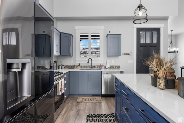 3278 S Serviceberry Dr Unit 18, Garden City, UT 84028 - kitchen with stainless steel appliances, a sink, blue cabinetry, hanging light fixtures, and wood finished floors