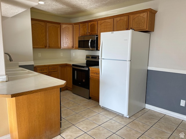 kitchen featuring brown cabinets, appliances with stainless steel finishes, light countertops, and a sink
