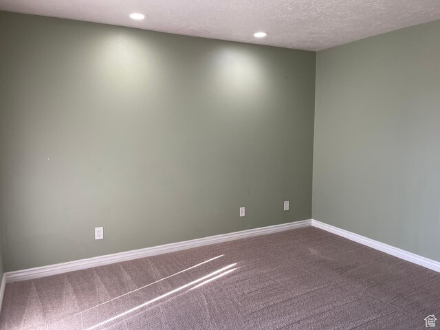 empty room with recessed lighting, baseboards, dark colored carpet, and a textured ceiling