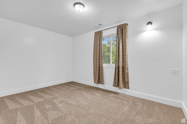 carpeted empty room featuring a textured ceiling, visible vents, and baseboards