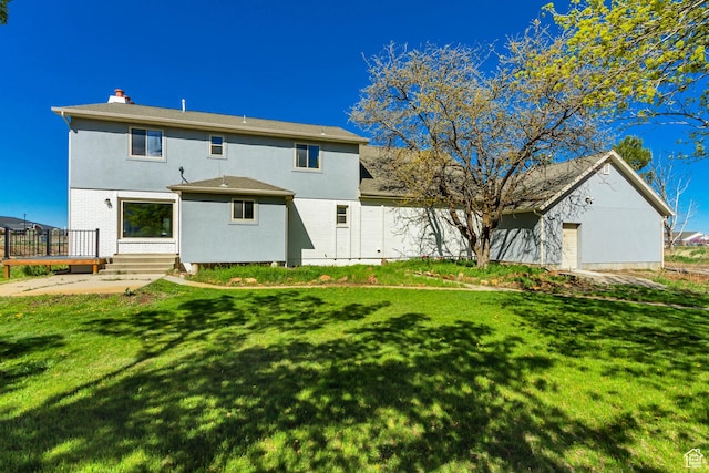 back of house with a lawn, a deck, stucco siding, and a chimney
