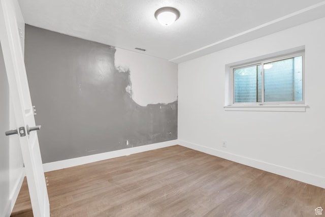 spare room with wood finished floors, visible vents, and baseboards