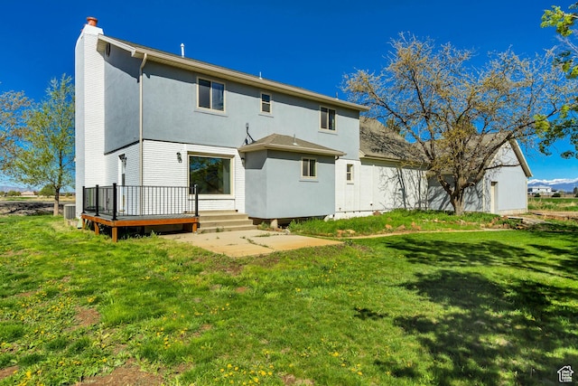 rear view of property featuring a chimney, stucco siding, a yard, central air condition unit, and a wooden deck
